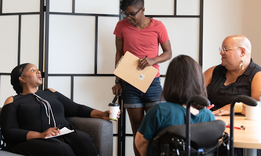 A group of diverse women sitting around a table in a meeting room.